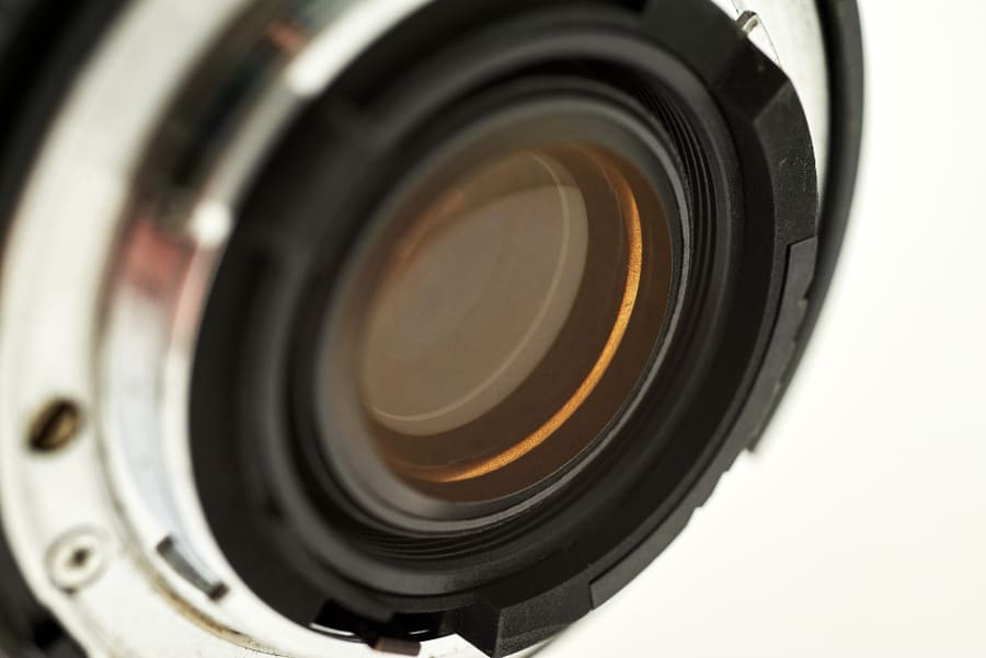 Frontlinse eines Objektivs im Detail, warme Spiegelung im Glas